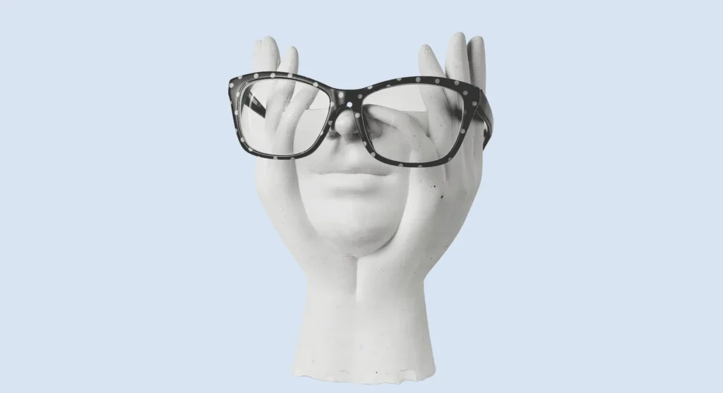 Plaster hands holding a face wearing reading glasses