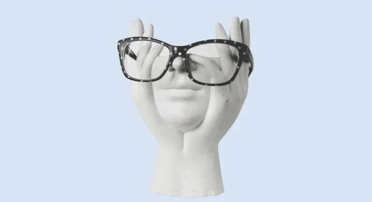 Plaster hands holding a face wearing reading glasses