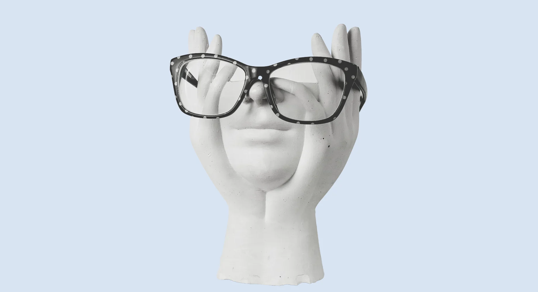 Plaster hands holding a face wearing reading glasses